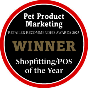 A circular award badge with a thick red outer ring and a black inner circle. White text at the top reads 'Pet Product Marketing' and below that, 'RETAILER RECOMMENDED AWARDS 2025'. In the center, the word 'WINNER' is displayed in large, bold, brown letters. Below 'WINNER', white text reads 'Shopfitting/POS of the Year'.